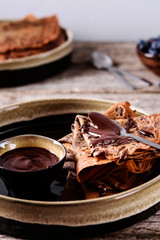 Chocolate Crepes with chocolate sauce and blueberry on vintage wooden table. Selective focus