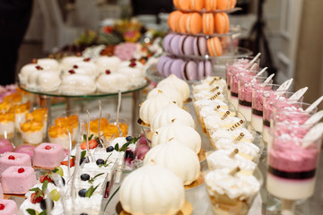Sweet dessert table or candy bar. Table with different sweets for party. Holiday buffet with cupcakes and other desserts. Macaron, cupcakes, marshmallow close up