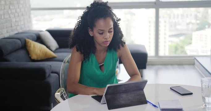 Young black business woman working with laptop computer at home. Anxious girl studying with pc. Nervous African American people and technology