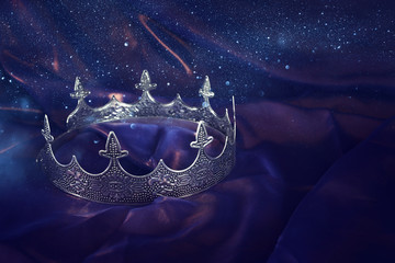 low key image of beautiful queen/king crown over dark royal purple delicate silk. fantasy medieval...