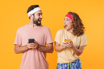 Portrait of athletic young couple smiling and using cellphones together