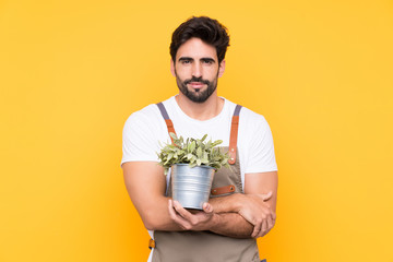 Gardener man with beard over isolated yellow background keeping arms crossed