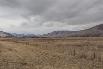 Vast open fields with cattle fencing in front of large rolling hill mountains