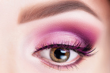 Fashionable bright eye makeup close-up. Female eye with violet shadows and false eyelashes