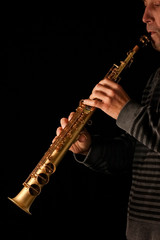 Naklejka premium soprano saxophone in the hands of a guy on a black background