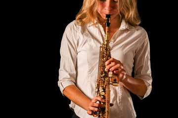 soprano saxophone in the hands of a girl on a black background