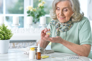 Portrait of sick senior woman sitting at table