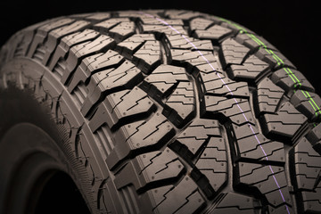 mud all terrain tires for SUVs on a black background close-up, emphasis on the wheel tread.