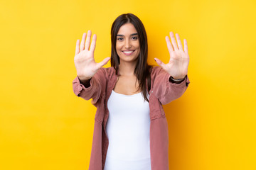 Young brunette woman over isolated yellow background counting ten with fingers