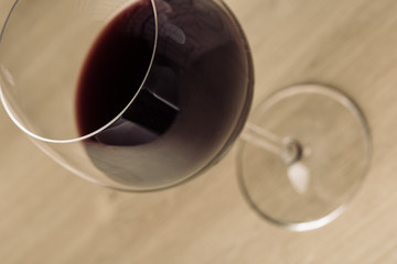 Red wine on a wineglass close up still on a blurry wooden plank surface