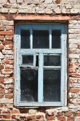 Old little window of blue color and a brick wall. Exterior of an old house