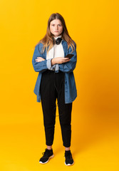 Student ukrainian teenager girl over isolated yellow background keeping arms crossed