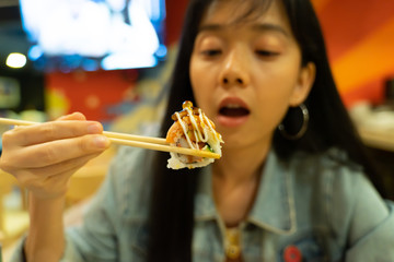 Asian woman eating sushi roll