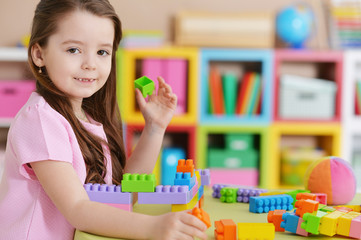 Close up portrait of cute little girl in pink shirt playing