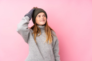 Ukrainian teenager girl with winter hat over isolated pink background laughing