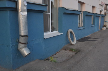 Blue Urban Wall with Gutter Pipe and Lonely Tire