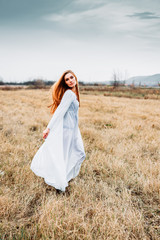 Fototapeta na wymiar Beautiful girl in white nightgown, looking like a fairy on corn field.