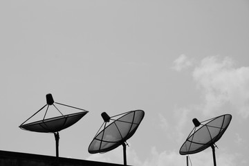 monochrome satellite dish on building with gray sky background and space for text