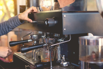 Hand of barista put on botton of coffee machine for provide hot coffee