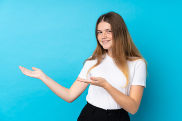 Ukrainian teenager girl over isolated blue background extending hands to the side for inviting to come