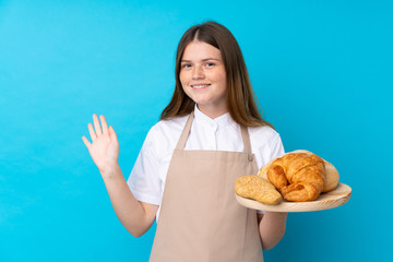 Ukrainian teenager chef uniform. Female baker holding a table with several breads saluting with hand with happy expression