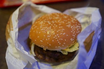 Close-up of man holding eating fastfood cheeseburger  
