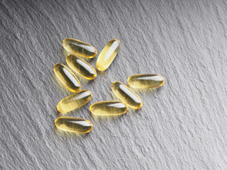 Many capsules Omega 3 on a gray stone background. Health care concept