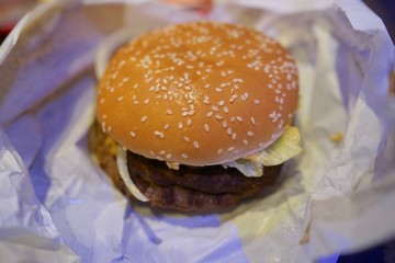 Close-up of man holding eating fastfood cheeseburger  