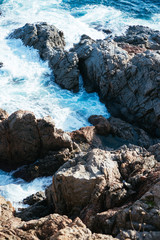 Aerial view of ocean waves and brown rocks in the coastline