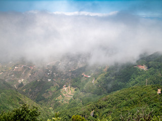 View from the high mountain overgrown with forest on clouds covering valley