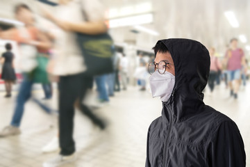 Fototapeta na wymiar Asian man wearing surgical mask to prevent flu disease Coronavirus with blurred image of people traveling