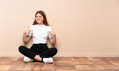Ukrainian teenager girl sitting on the floor proud and self-satisfied