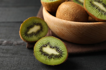 Bowl with ripe kiwi on wooden table, close up
