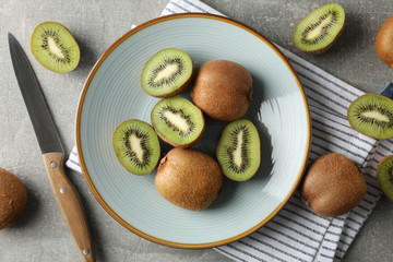 Composition with plate of ripe kiwi on grey table, top view