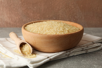 Bowl with rice, towel and spoon on grey table, close up