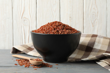 Bowl with rice, towel and spoon on wooden table, space for text