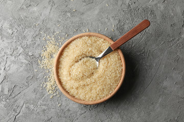 Bowl with rice and spoon on grey background, top view