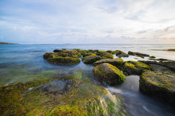 Fototapeta na wymiar Seascape. Beach with rocks and stones. Low tide. Slow shutter speed. Soft focus. Melasti beach, Bali, Indonesia