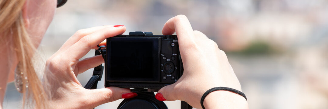 Woman holding small digital camera trying to take travel photo