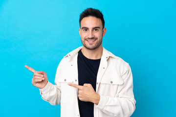 Young handsome man over isolated blue background pointing finger to the side