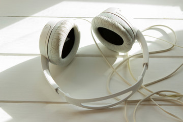 white gray big headphones are on a white wooden table. In-ear headphones for playing games and listening to music tracks.