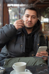 Young man smokes in a cafe - obrazy, fototapety, plakaty