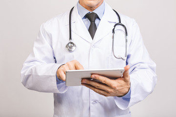 Portrait of a cheerful smiling senior medical doctor with stethoscope using pc tablet isolated on grey background.