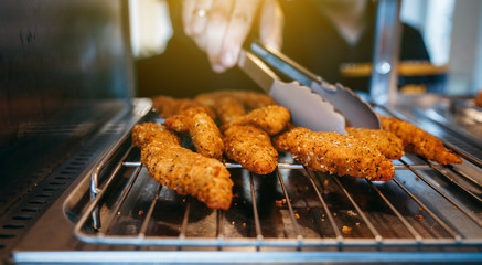 Chef's hand taking Crispy chicken nuggets close-up in a restaurant