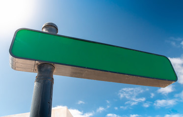 Closeup image of empty blank directional sign on street against clear blue sky and sun. Copy space....
