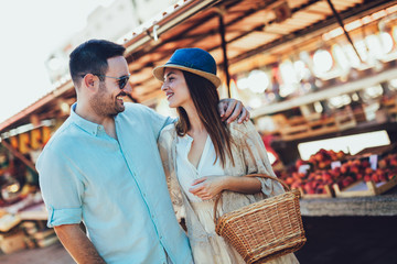 Young couple buying fruits and vegetables in a market on a sunny morning.