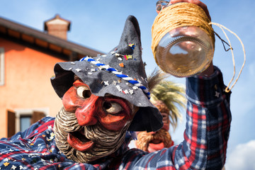 Portrait of a masked man holding an empty wine bottle. Happy drunk man in traditional pagan...