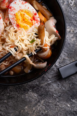 spicy instant noodles soup with shrimps, egg and  mushrooms. served  by black chopsticks. flat lay. close up