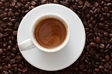 White cup of coffee and dark roasted beans. Closeup, top view. Coffee shop, espresso, fresh roast, drink  concept