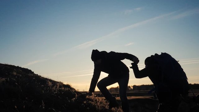 teamwork help business three men hold hand travel silhouette concept. group of tourists lends a helping hand climb the cliffs mountains. people climbers climb to the top overcoming teamwork hardships